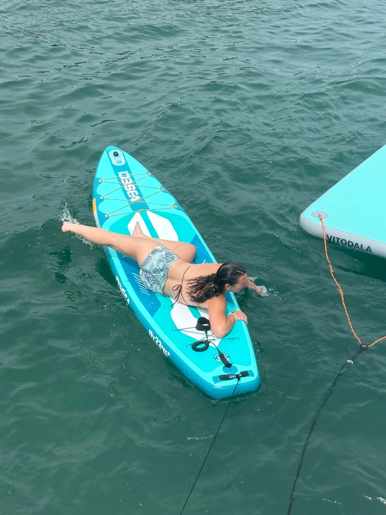 A guest relaxing on a turquoise paddleboard on the water